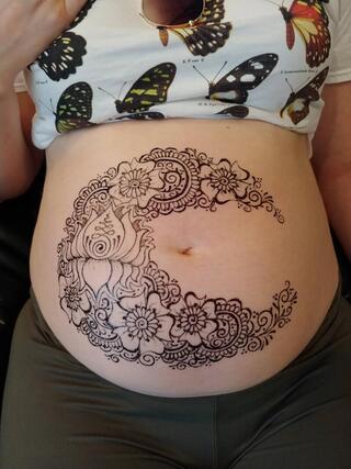 Belly henna like a moon with lotus flower for birthing or maternity celebration