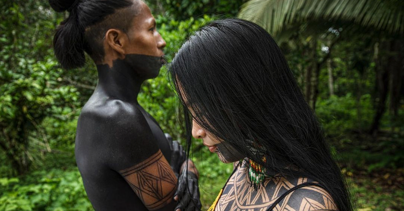 man and woman in jungle covered in jagua body art in indigenous patterns 